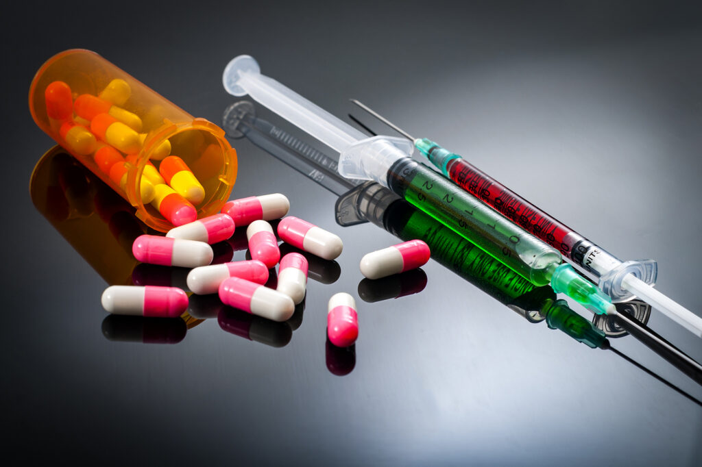 Syringes and pills on a dark background.