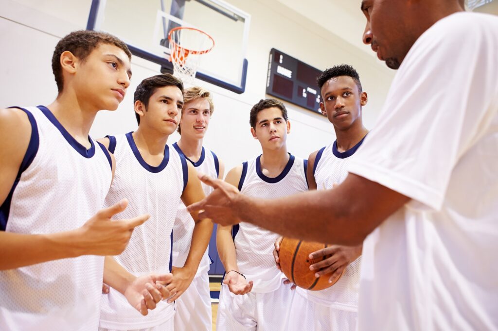 Male coach talking to young male basketball team.