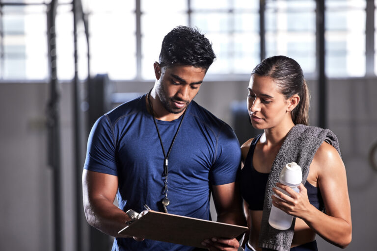 Coach and athlete discussing training plans in a gym setting.