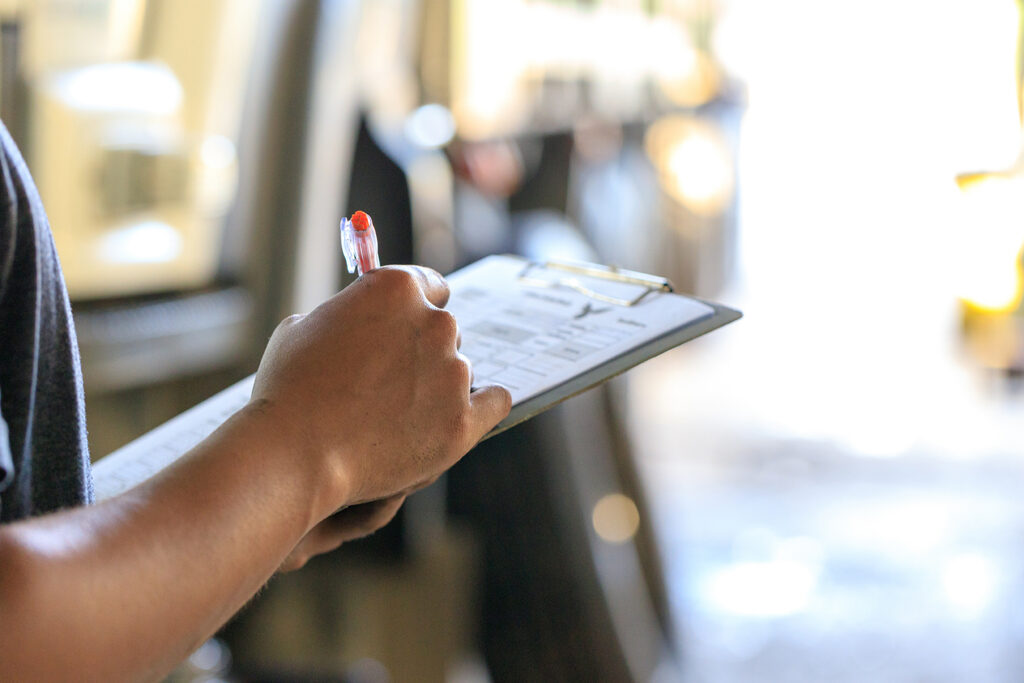 Person writing on a clipboard related to sports education and clean sport initiatives.
