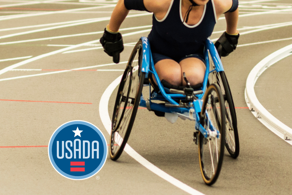 Athlete in a racing wheelchair on a track with the USADA logo.