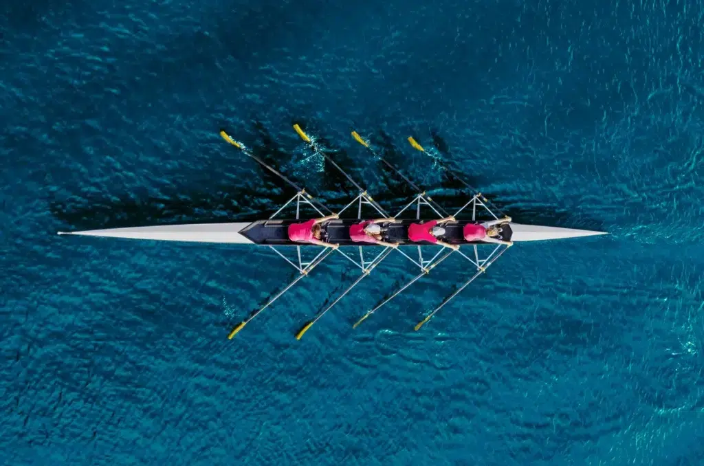 Aerial view of a rowing team on blue water.